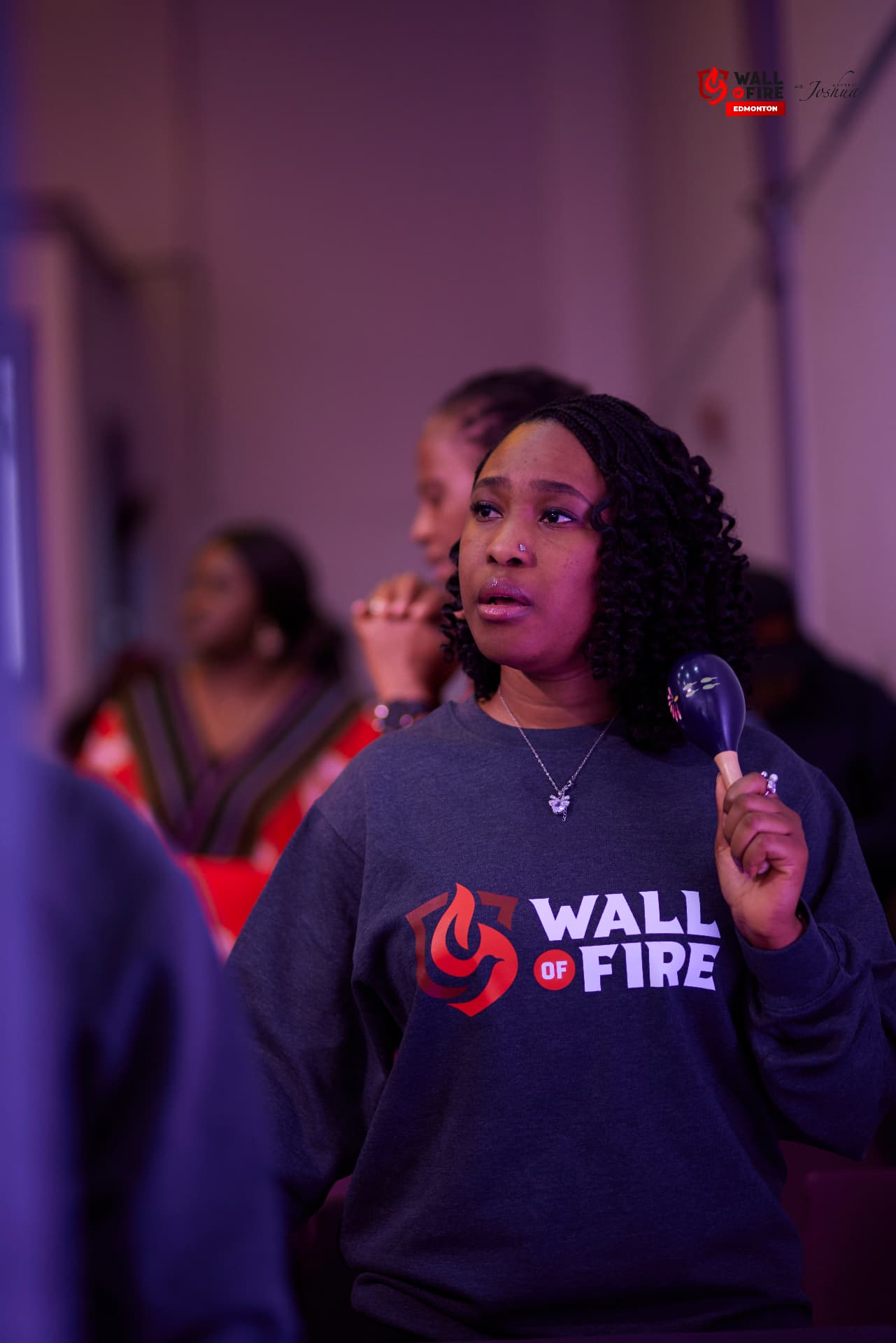 A worshipper in a Wall of Fire sweatshirt with a shaker